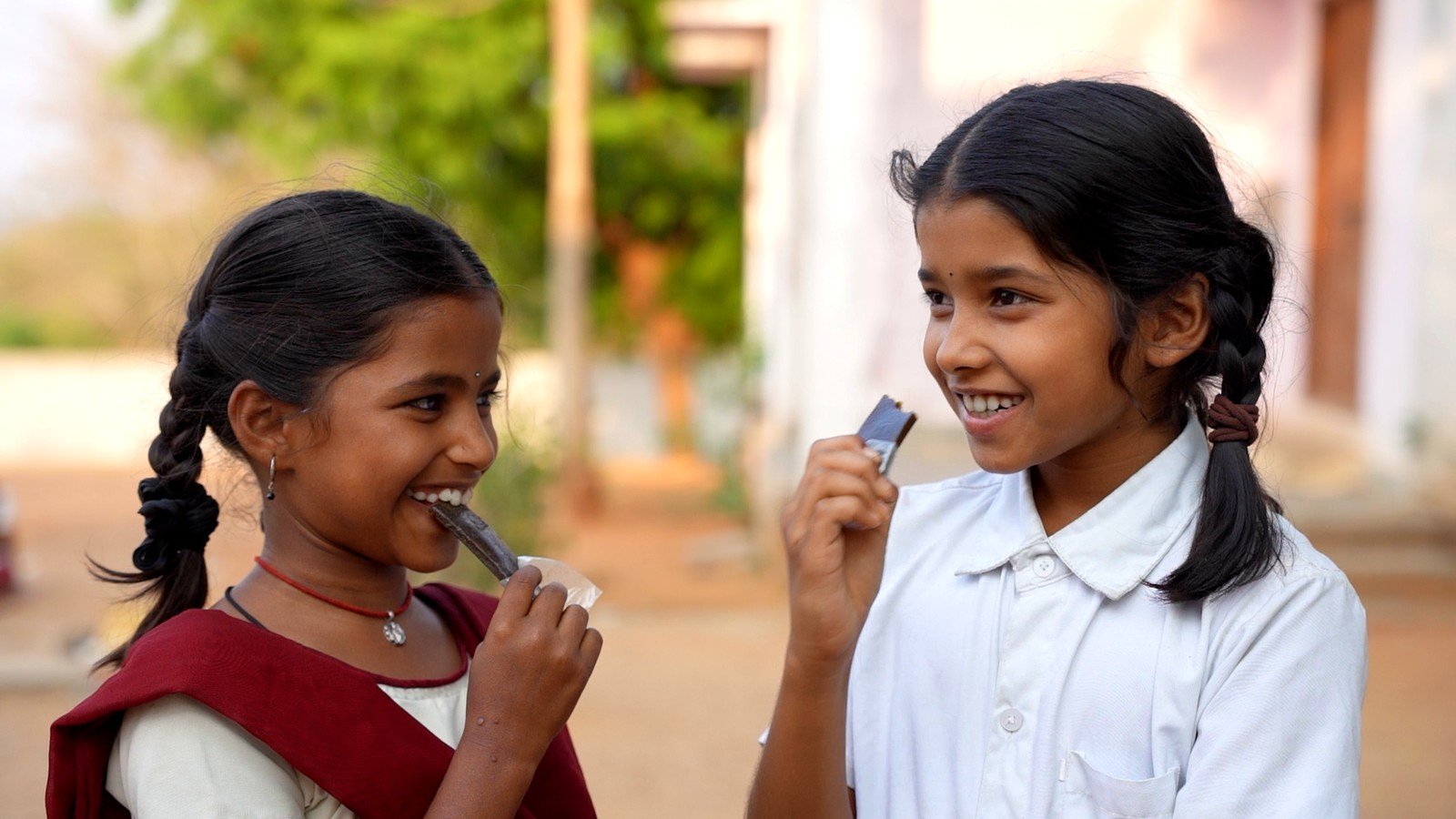 Two schoolgirls sharing a laugh while eating the Mosachi Natural Iron Fruit Bar